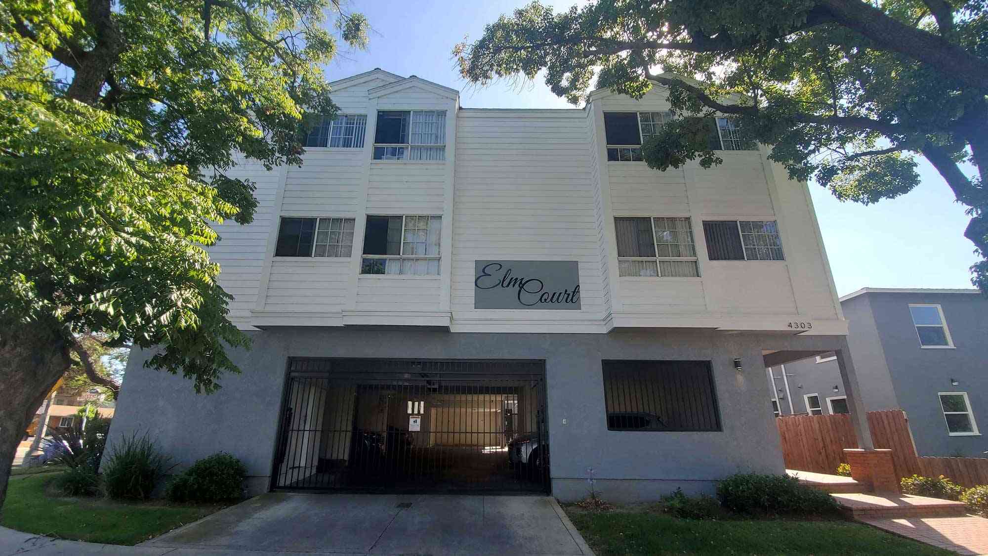 elm court apartments exterior building facade with gated parking entrance