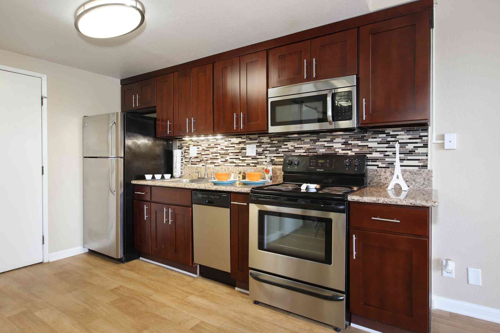 the bixby apartments renovated kitchen with dark wood cabinets and stainless steel appliances