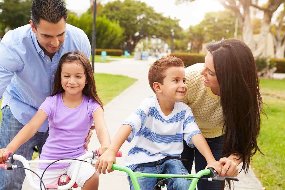 Family riding bikes together in the park near The Long Beach Collection